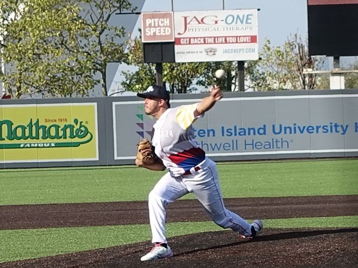 An infielder throwing across the diamond at a ballpark, outfield advertising boards behind him.