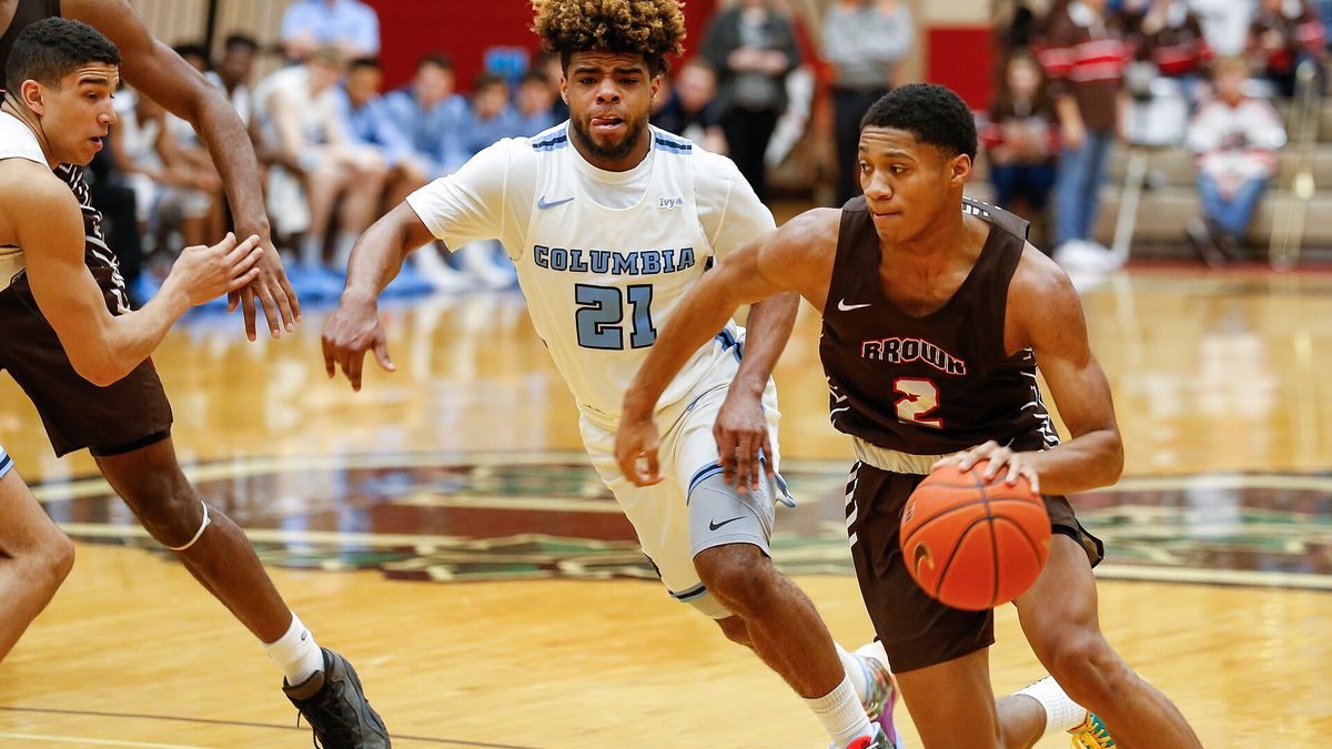 A college basketball player driving to the basket past a defender.
