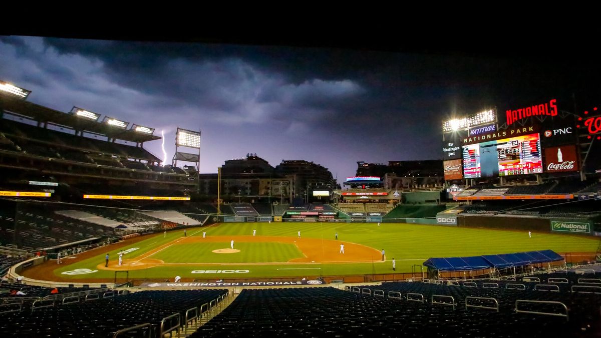 A ballpark under floodlights at dusk, seen from the upper stands.