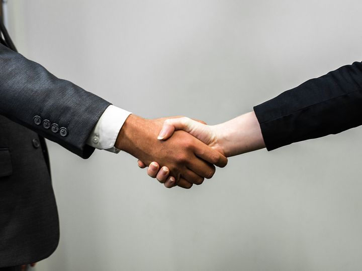 Two people in suits shaking hands.